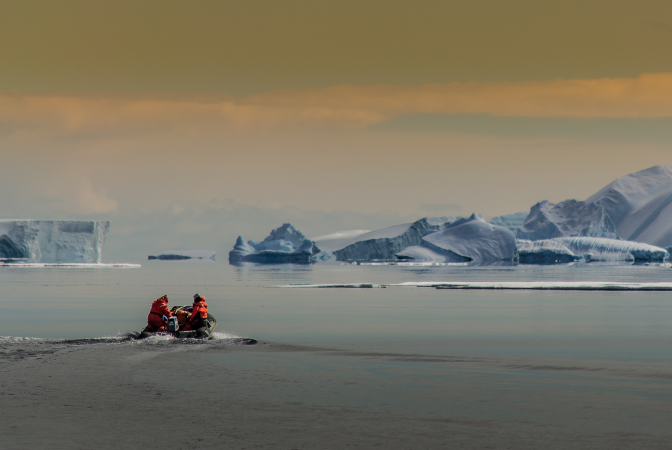 People in small boat appraching icebergs