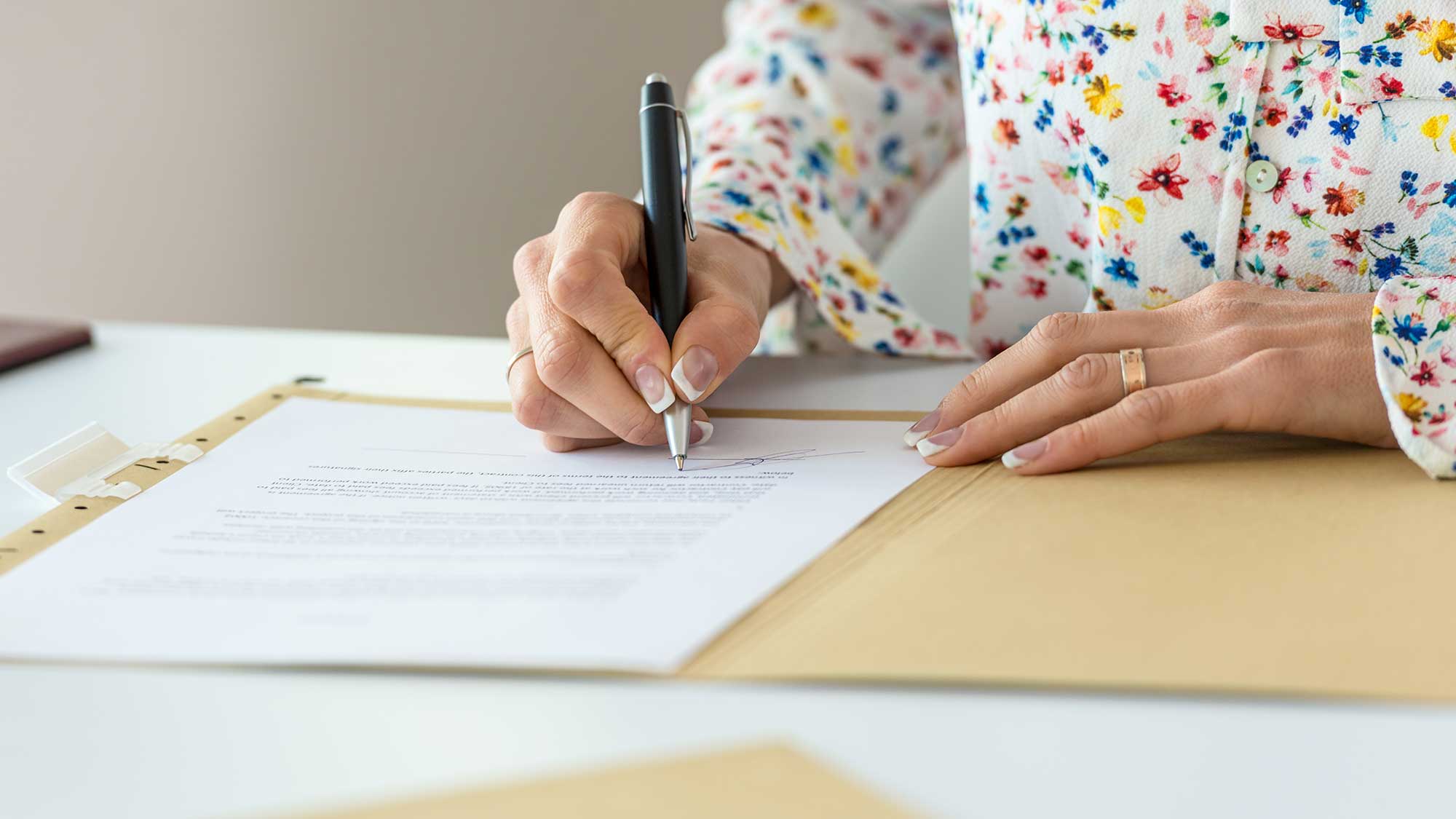 A person writing at a wooden table