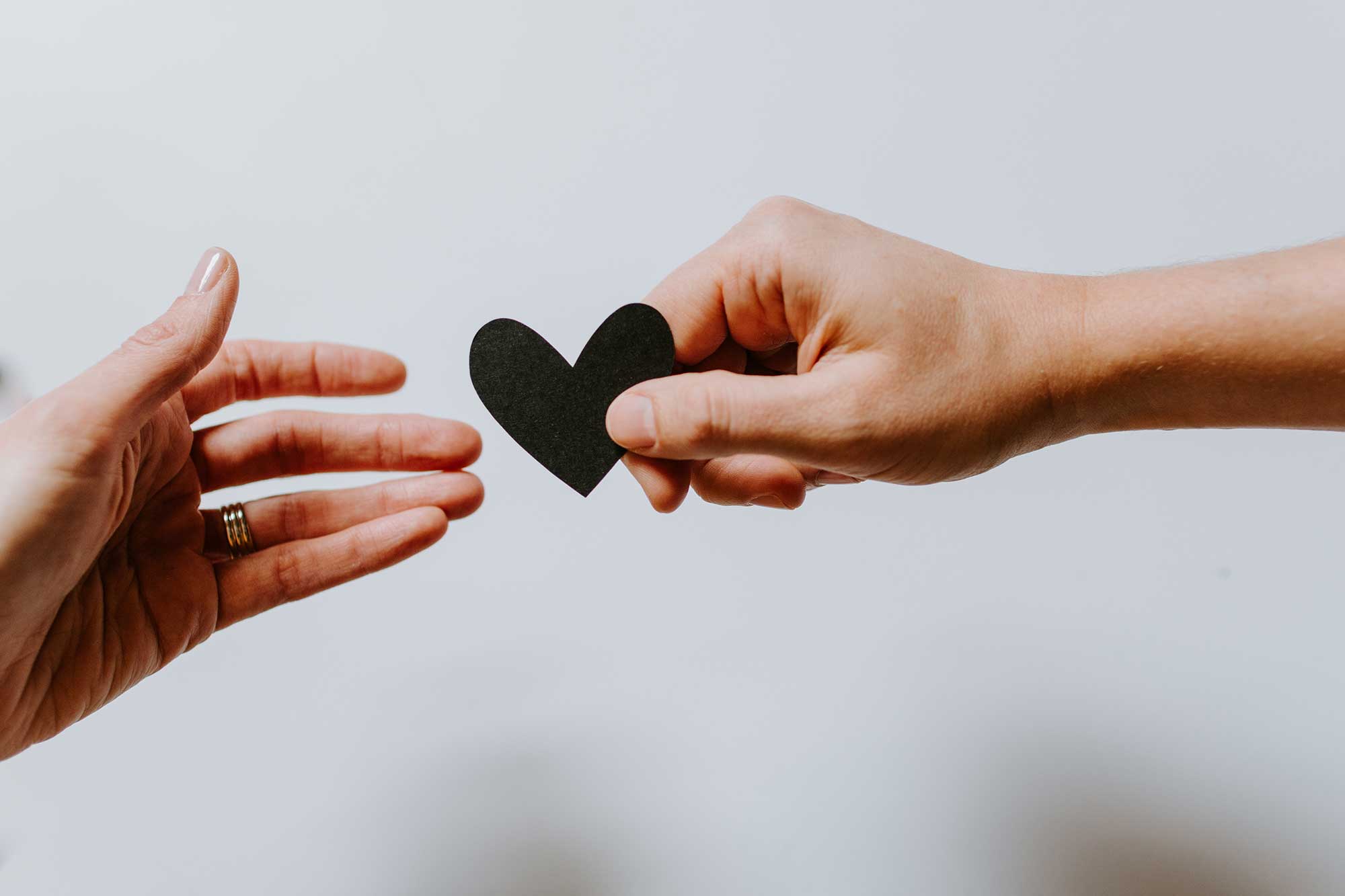 A hand giving a heart shaped piece to another hand