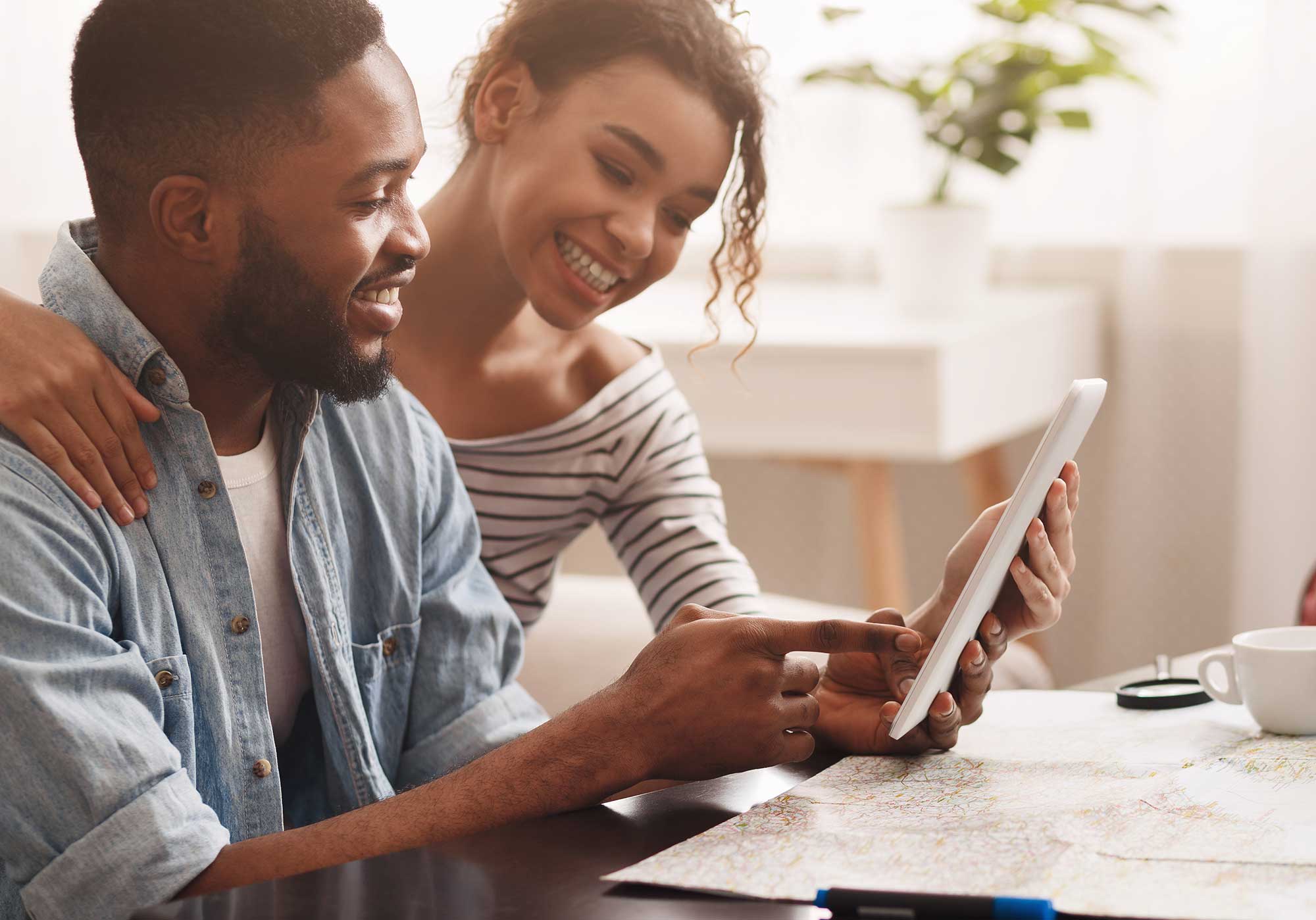 A man and a woman using a tablet computer and map to plan a vacation