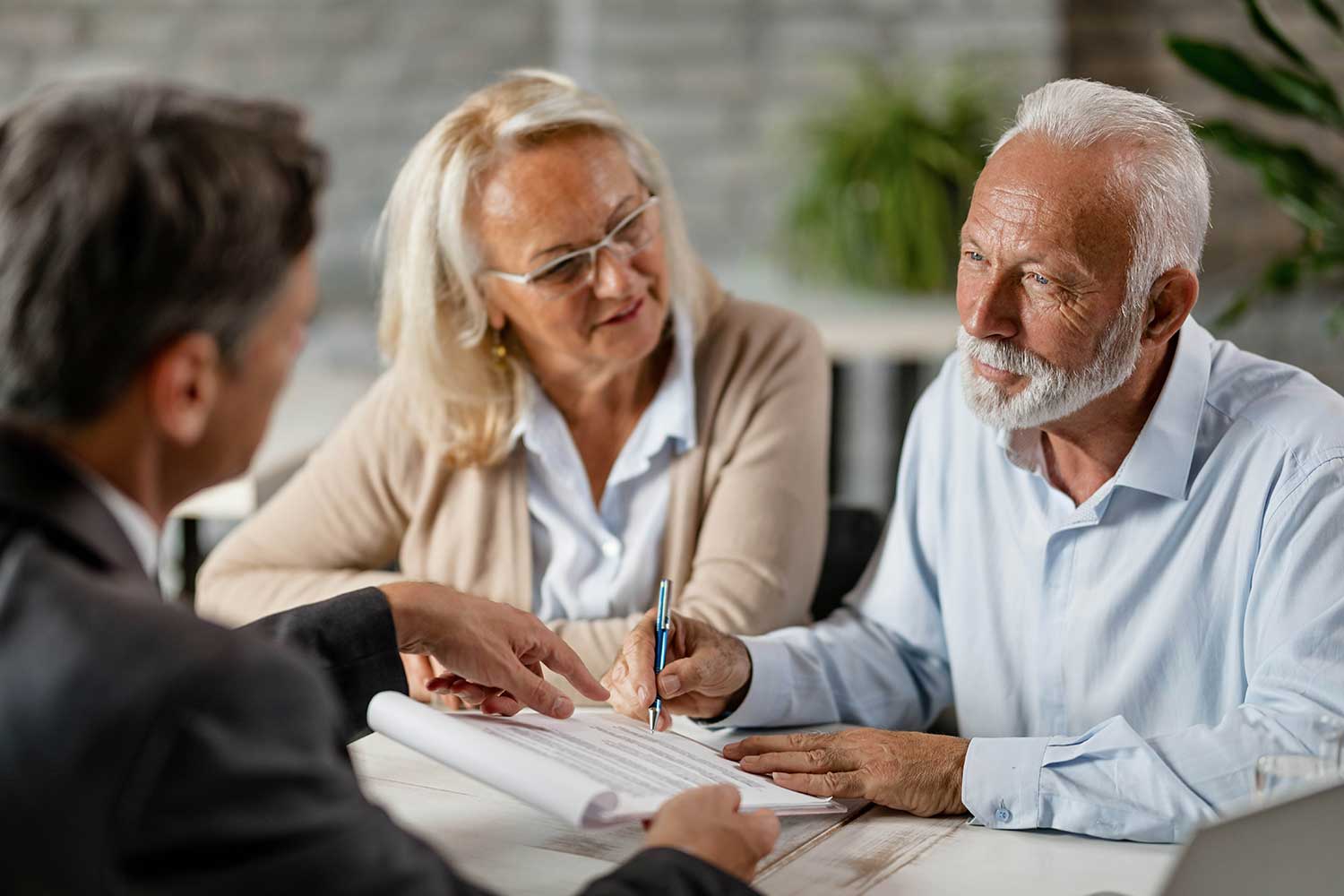 A man and a woman signing a paper with a financial advisor