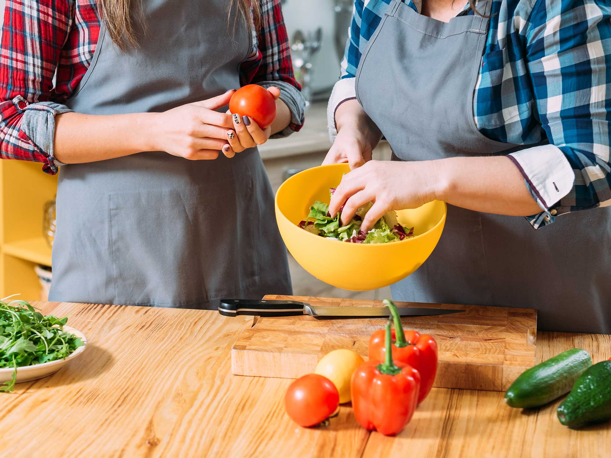 People chopping vegetables at a wooden table