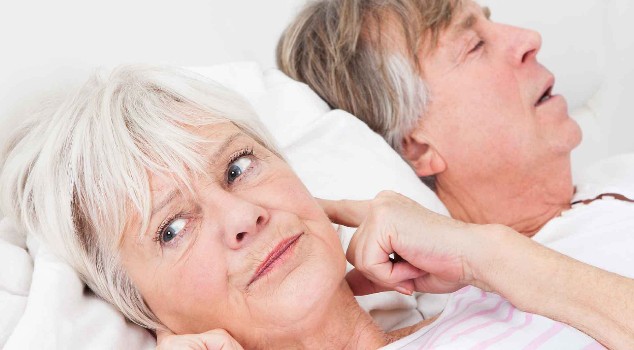 Woman frustrated with husbands snoring, covering her ears