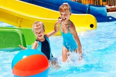 Kids playing in the water with a ball.