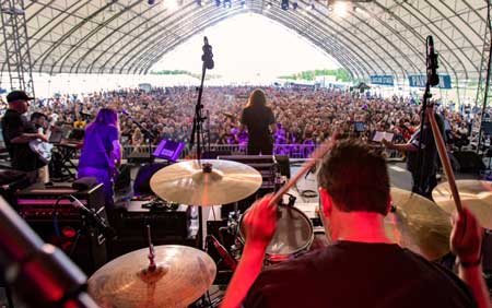 Image of a concert from the GearFest music festival. The photo is taken from the back of the stage and we can see the musicians and the audience