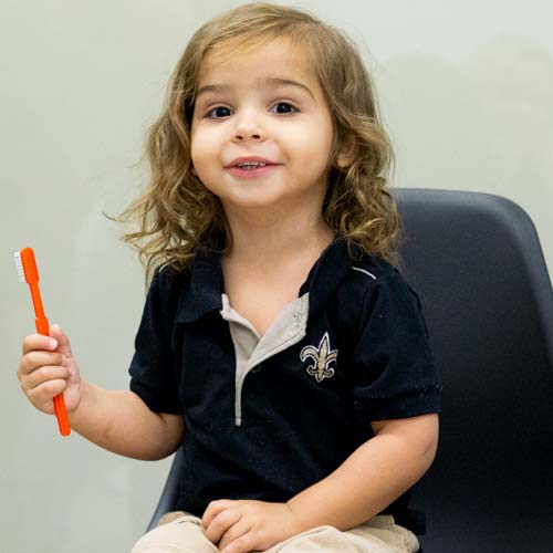 Child patient smiling with toothbrush in hand