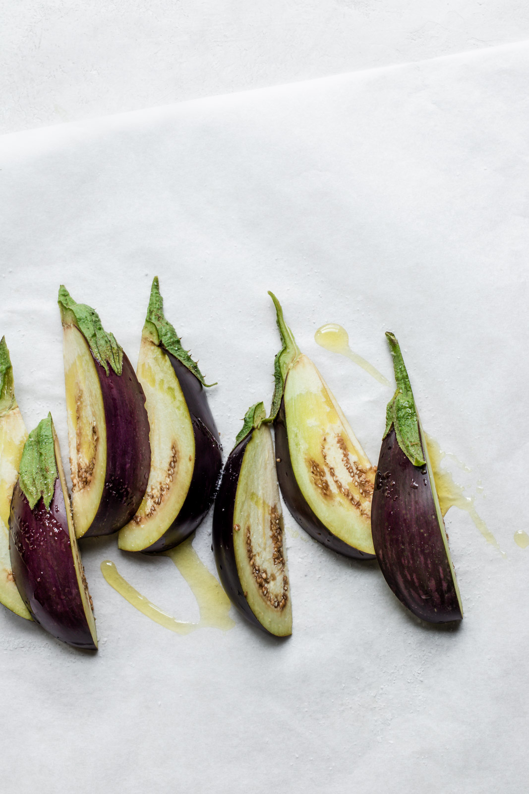 Row of purple eggplant wedges drizzled with olive oil