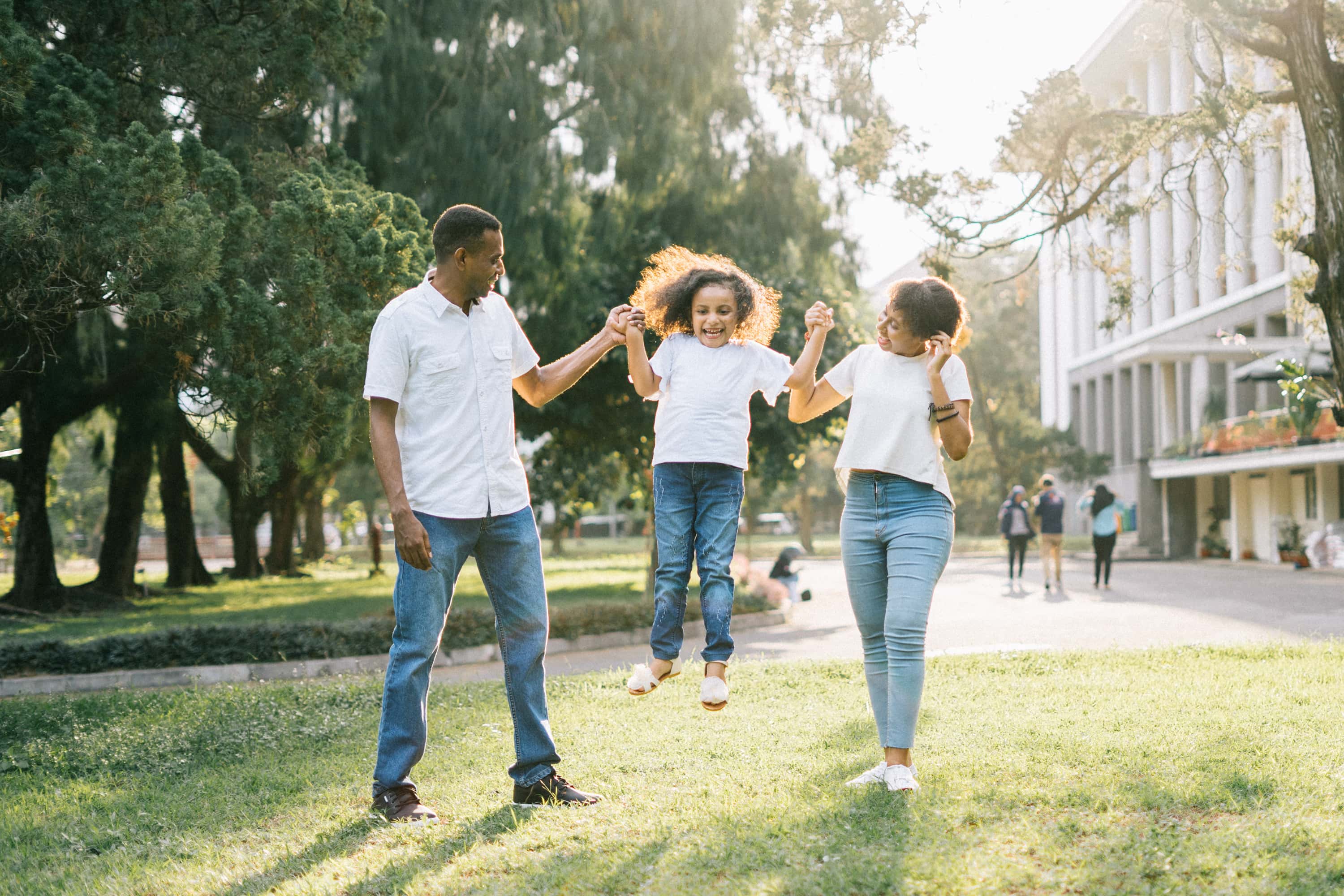 A family walks through a park holding hands.