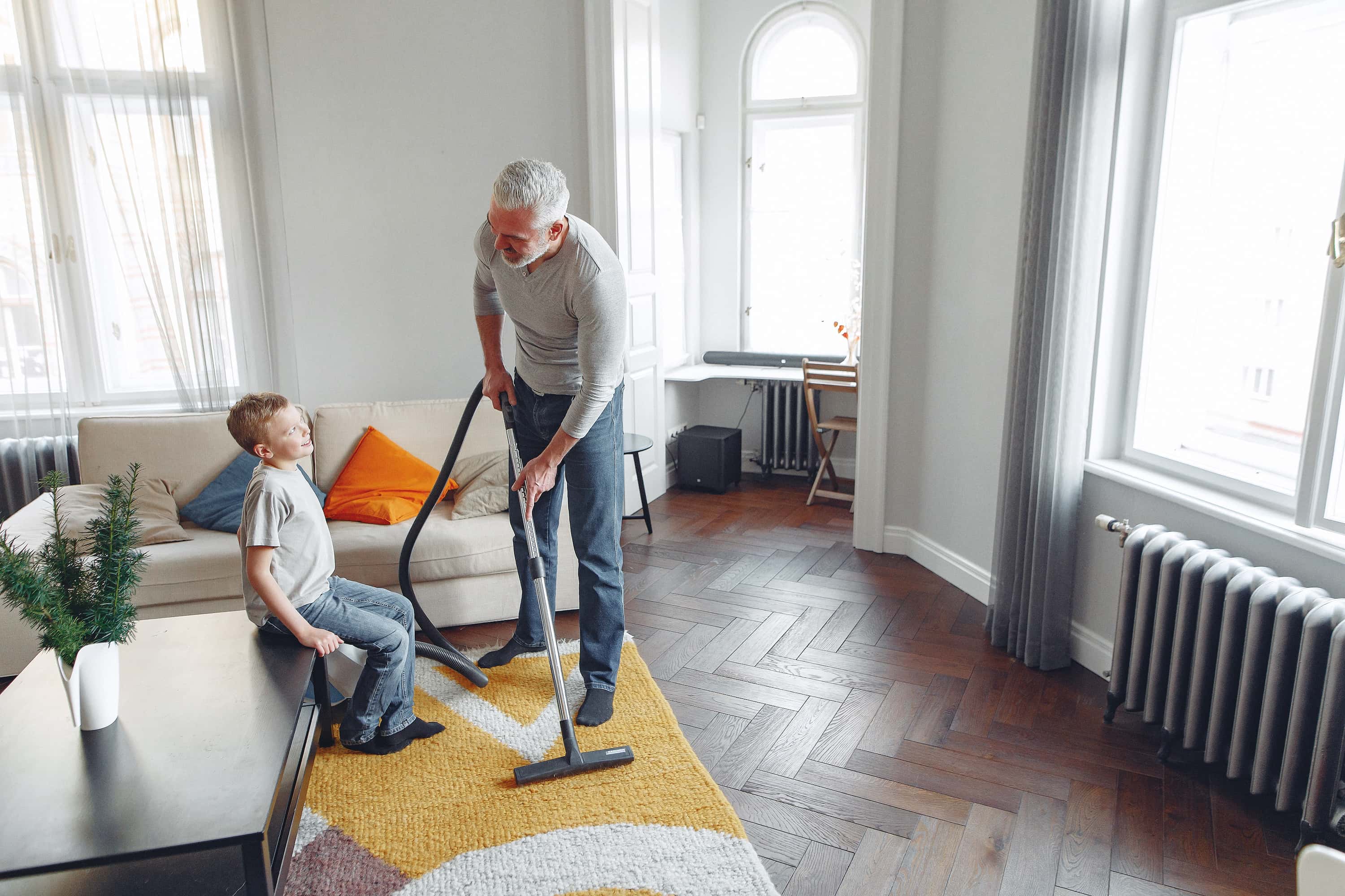 A man and his son vacuum together.