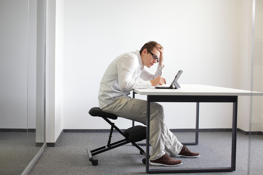 Young man is bent over her tablet in his office,seating on kneel
