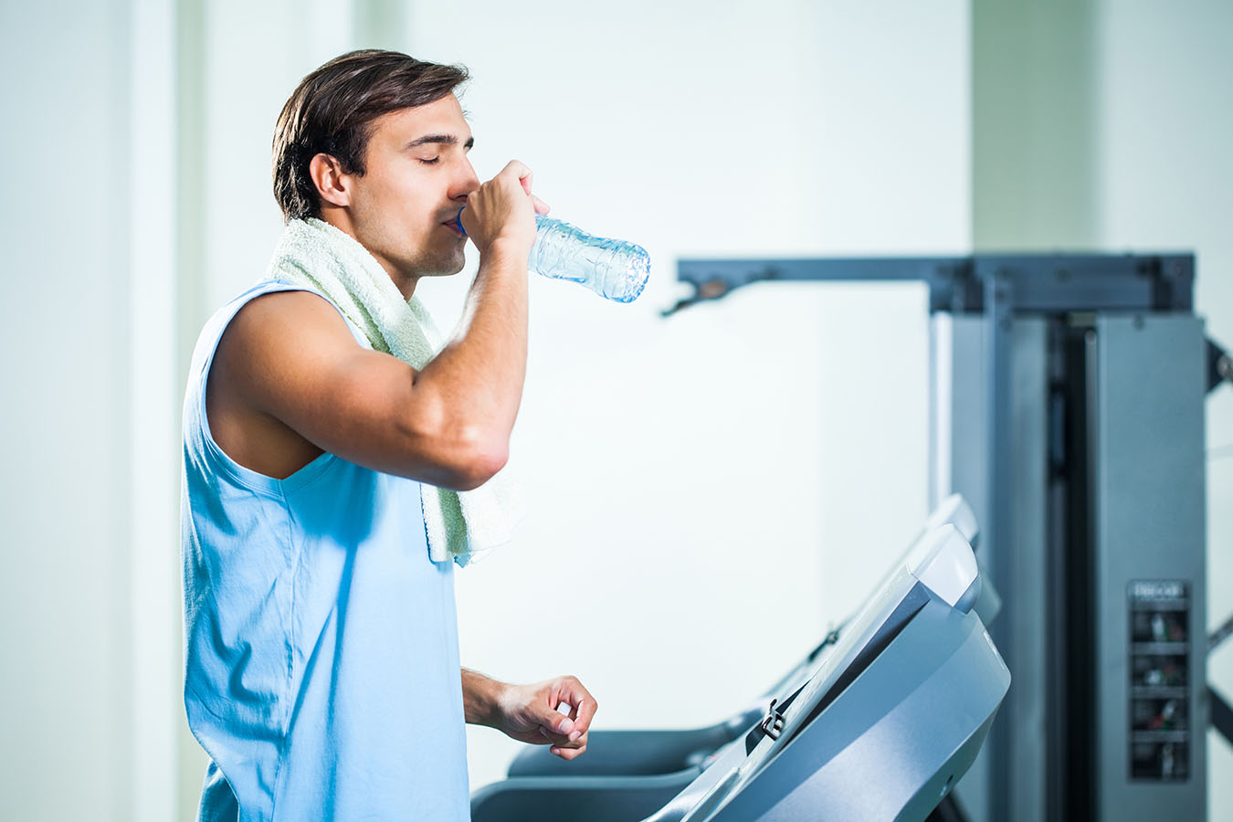 Man drinking water while exercising in gym