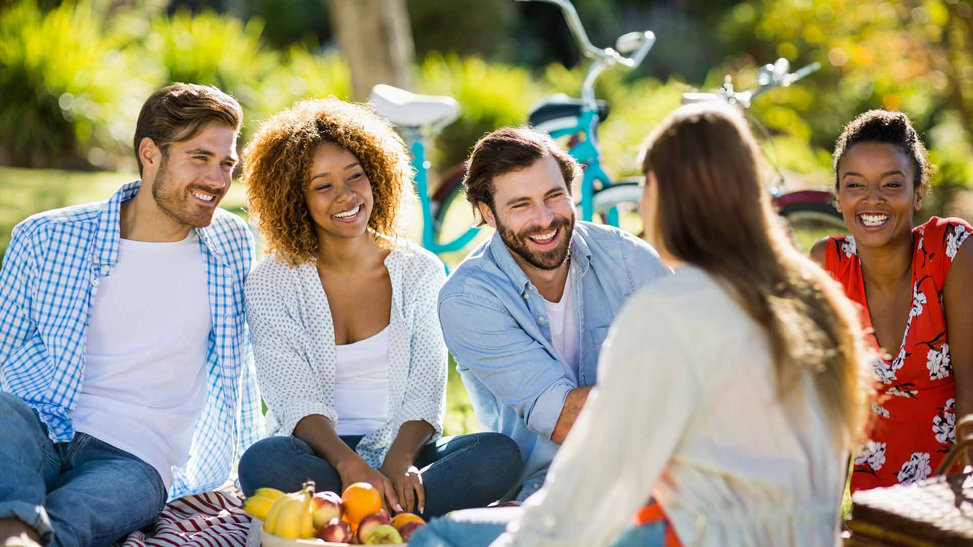 Young people sitting in a park laughing and talking