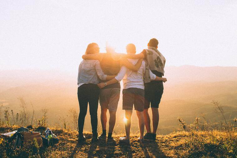 Freundschaftliche Umarmung von vier Personen in der Natur