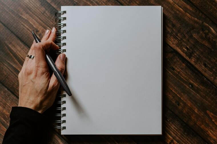 Abbildung eines Notizblocks und einer Hand, die einen Stift hält