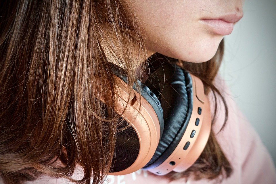 Photo by Gavin Whitner close up photo of teen with long hair and head phones
