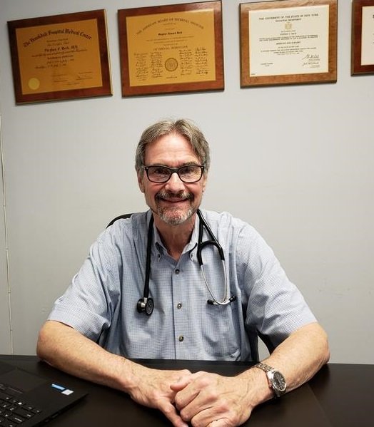 Medical Doctor Stephen Beck, MD, in office with degrees on wall