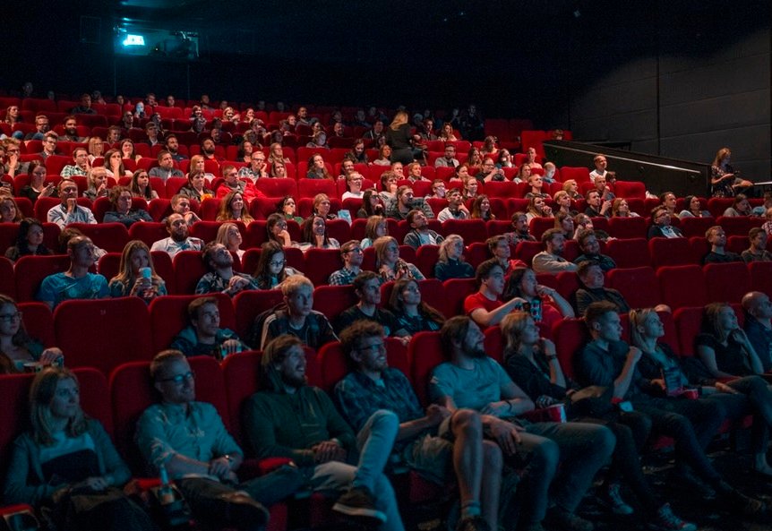 many people sitting in stadium seating theater watching movie