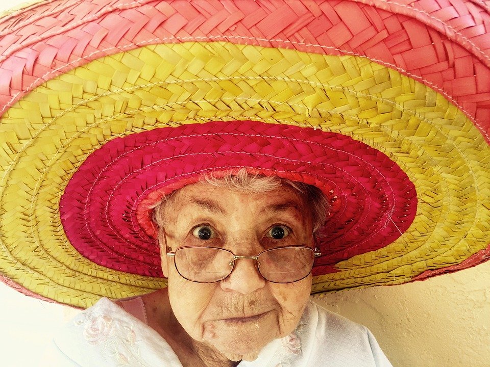 elderly woman trying on a colorful pink and yellow sombrero
