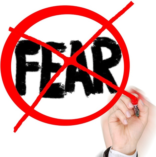 spray painted word FEAR crossed out with red circle and X drawn by a hand with a red marker