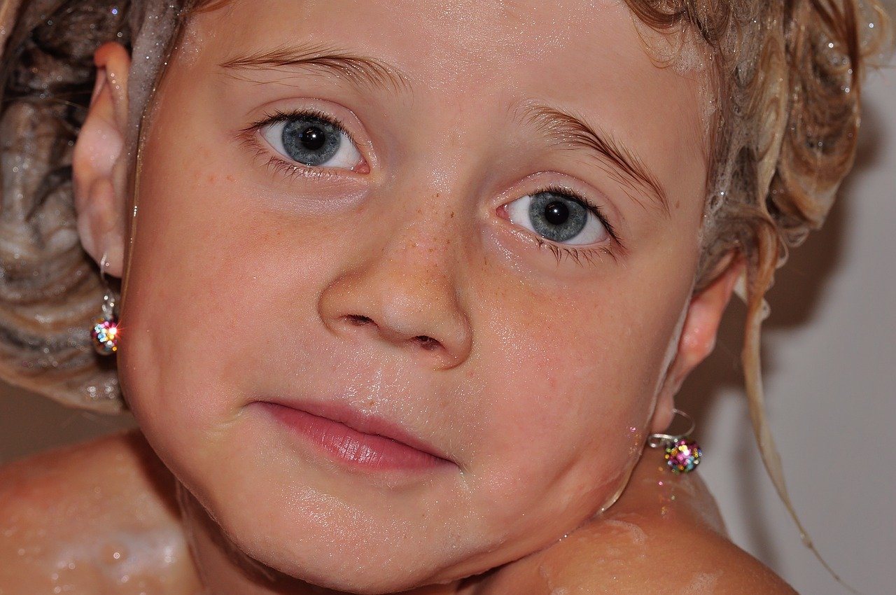 closeup of girl with wet face and sudsy hair.