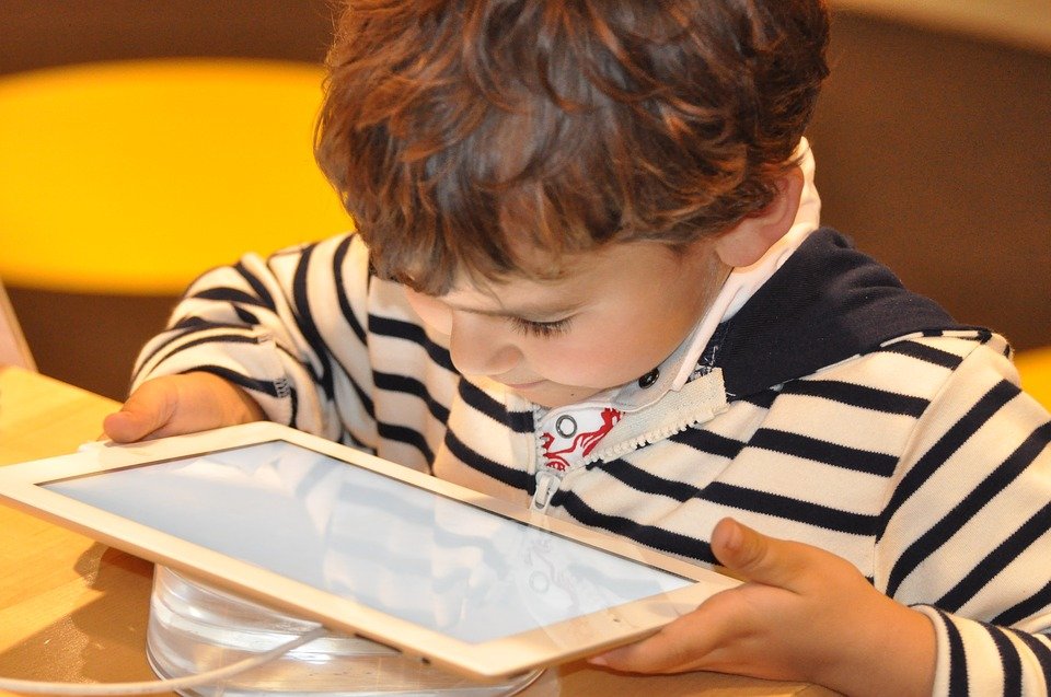 downward view of a young child looking at a tablet like an iPad.