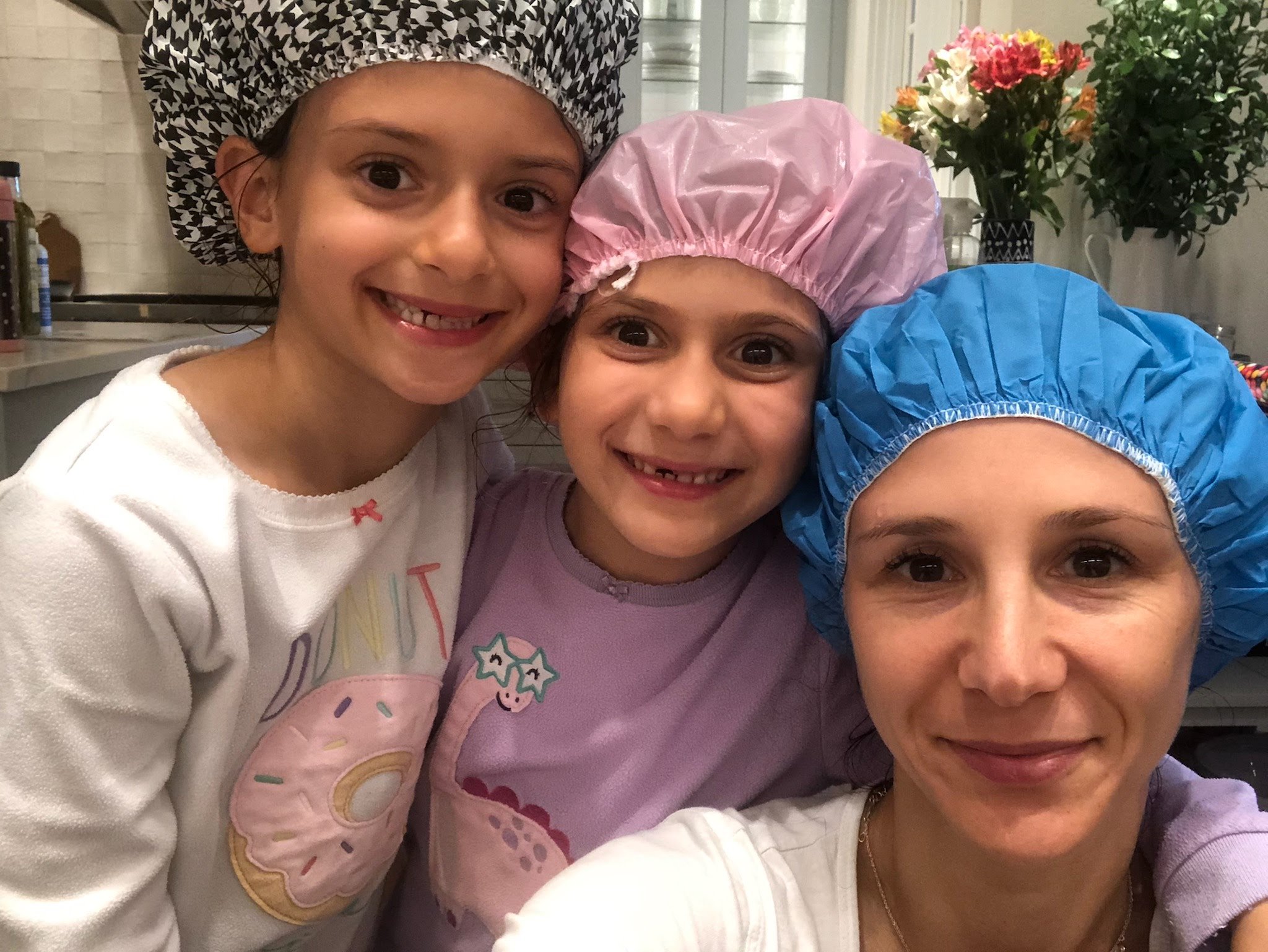LiceDoctors Technician taking head-to-head selfie with two smiling little girls, all wearing shower caps