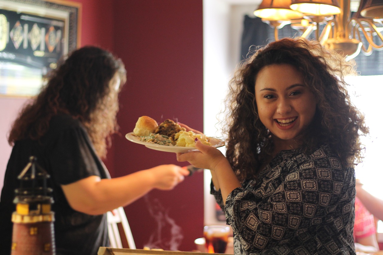 Family dinner like Thanksgiving, smiling woman holding a plate of food.