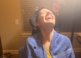 Soft focus LiceDoctors Technician treating client with head thrown back laughing