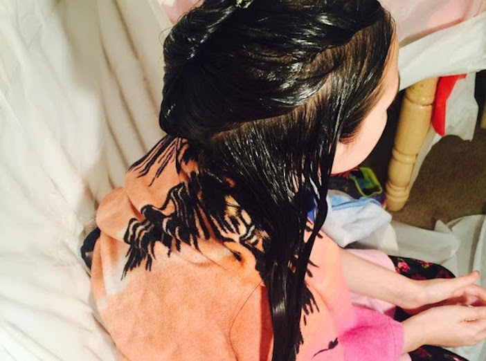 overhead view of child with long dark brown black hair oily oiled for LiceDoctors treatment.