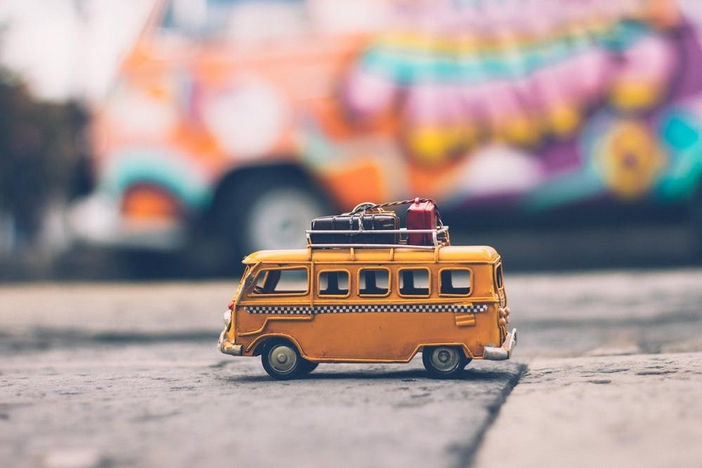 close image of a yellow toy retro antique van with soft focus antique van in background.
