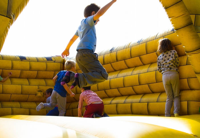 children bouncing in a yellow inflated bouncy house play room.
