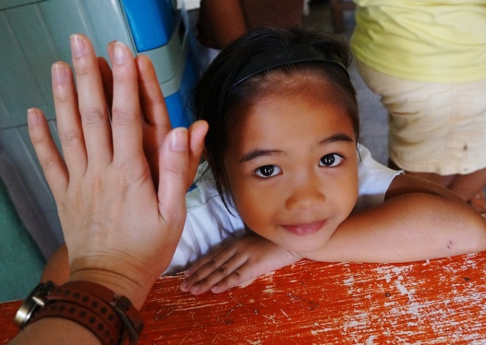 adult hand high-five with small child looking up at the camera.