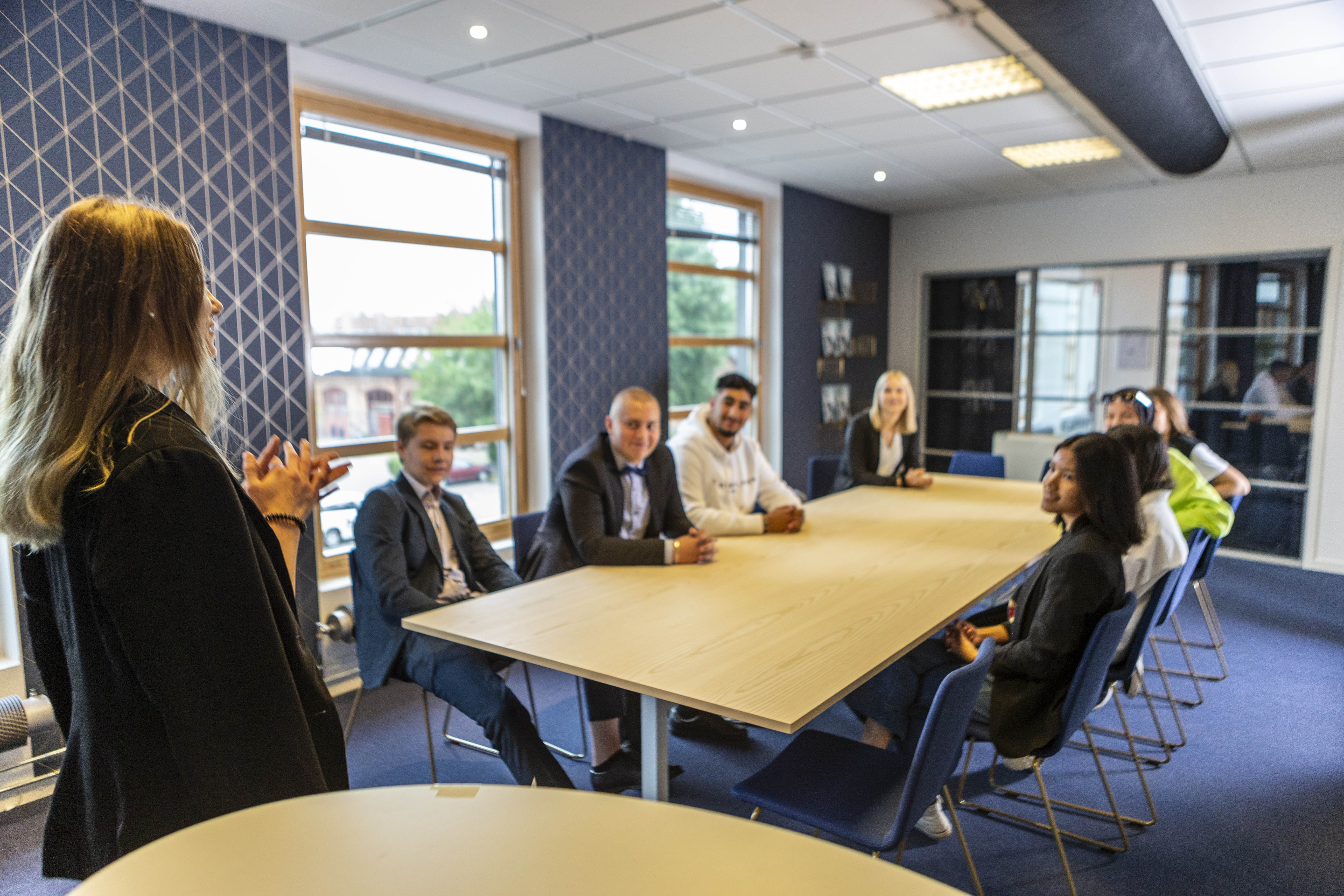 Kvinnlig elev står framför andra elever och håller föredrag i en konferenssal