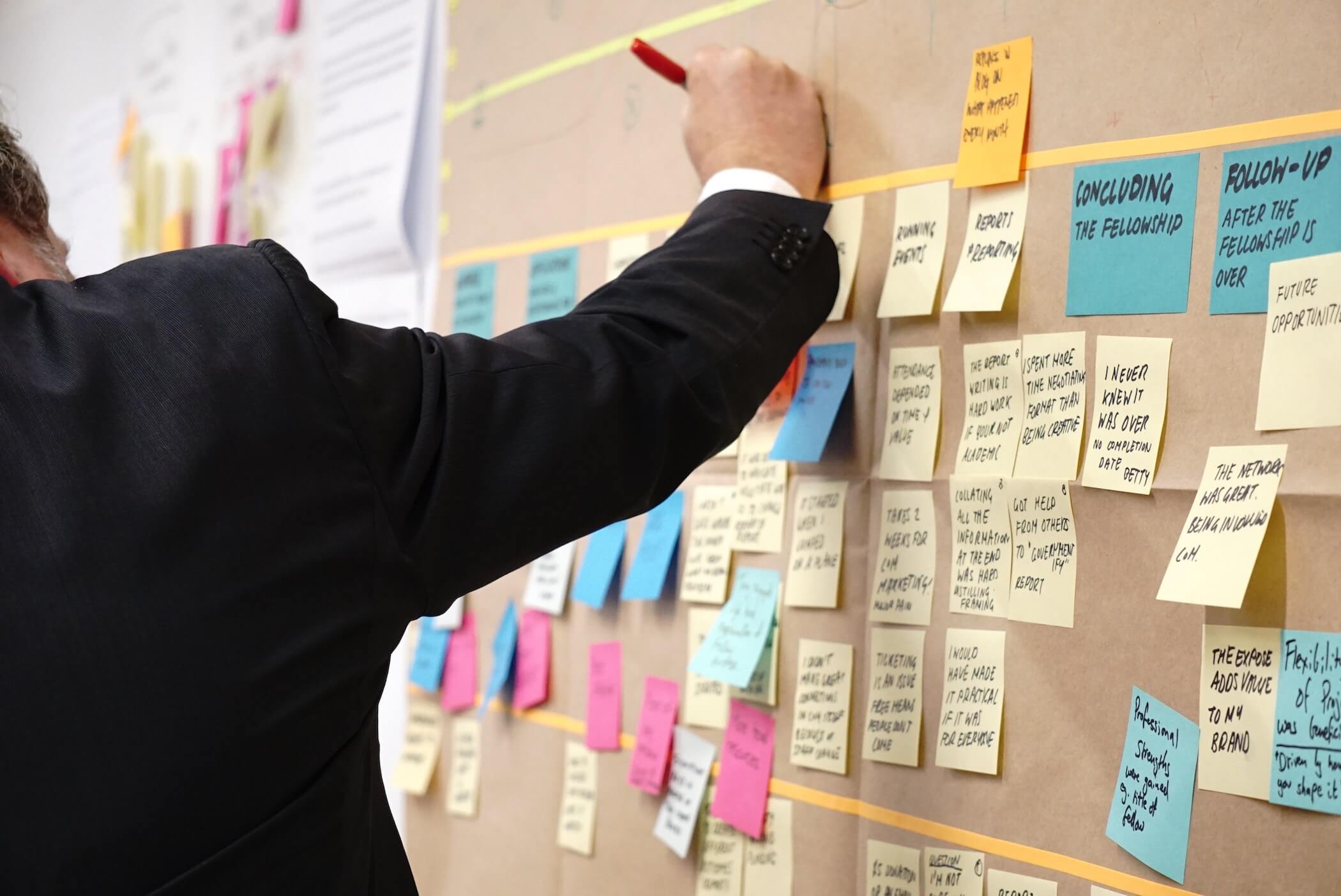 Projektleiter, der Post It Zettel an eine Wand klebt