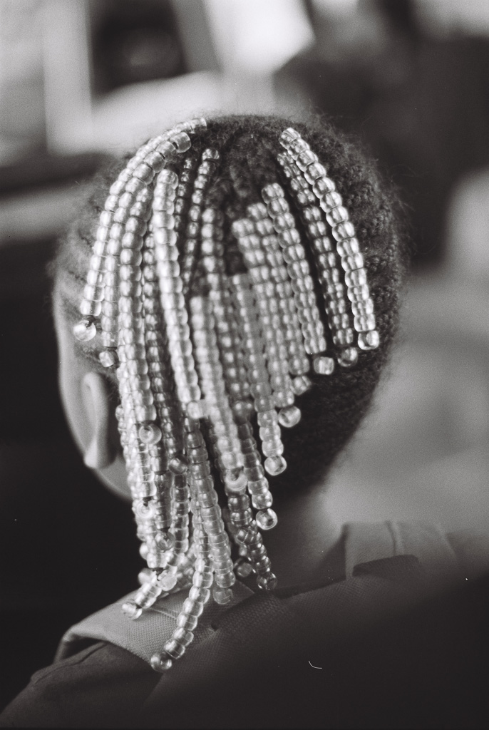 Young black girl riding the train with beads in her hair.