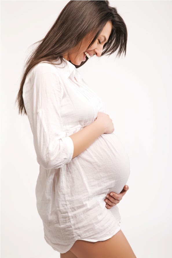 Happy pregnant female with hands on abdomen