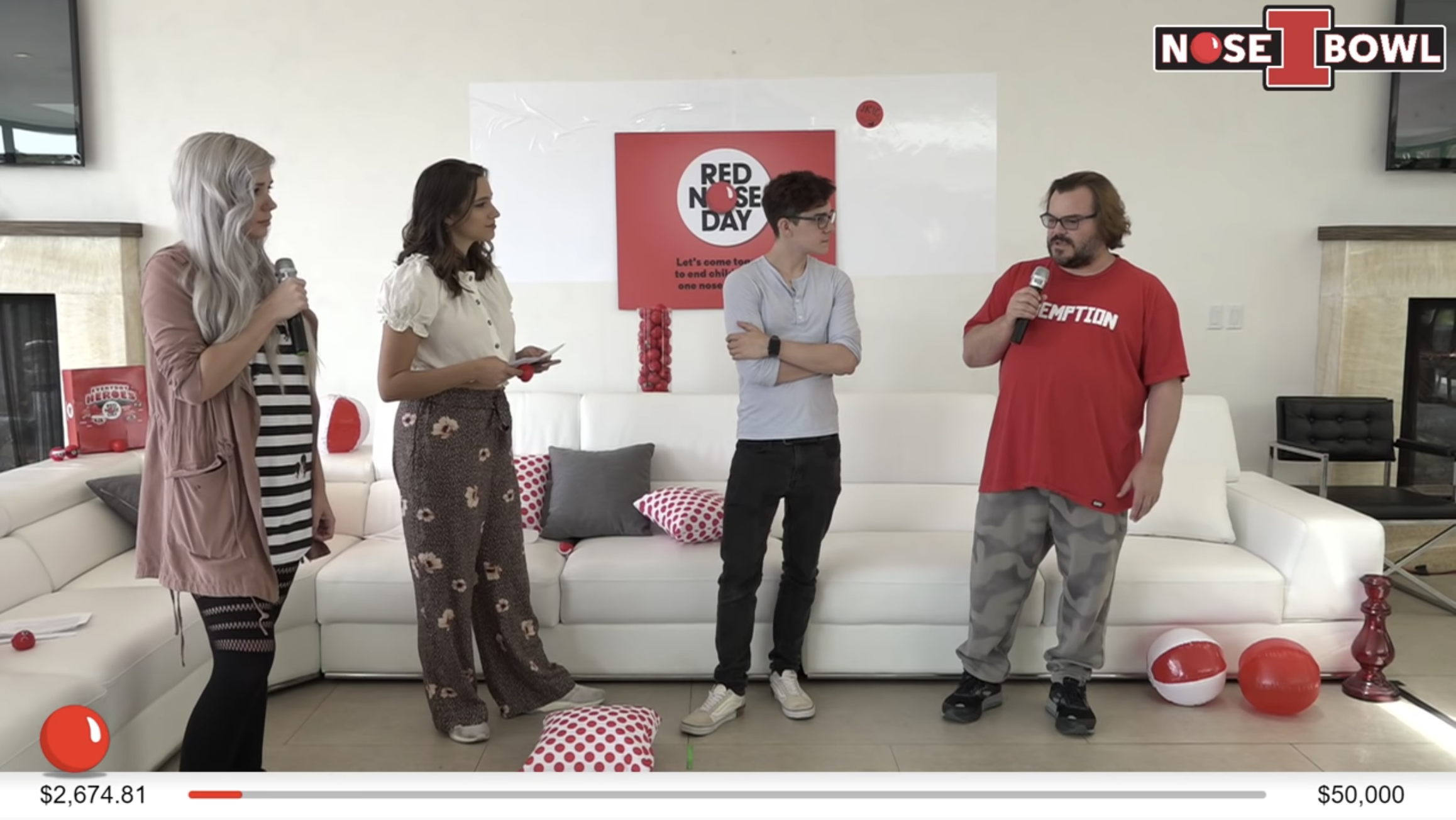 Still image of Red Nose day livestream. Jack Black holds a microphone and talks to three other guests. A live donation meter at the bottom indicates that they have raised $2,674.81 a $50,000 goal.