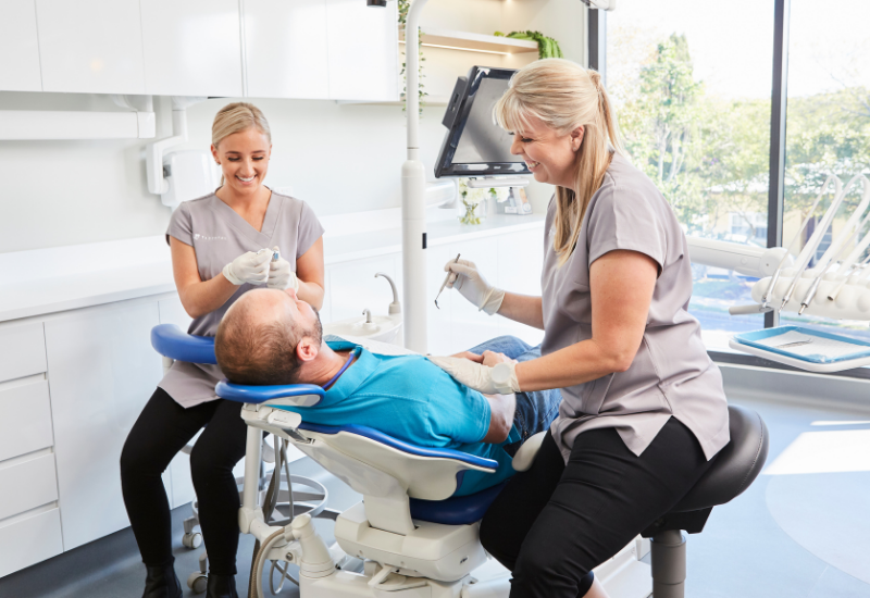 A patient learns about tooth extraction aftercare from a dental hygienist at TL Dental