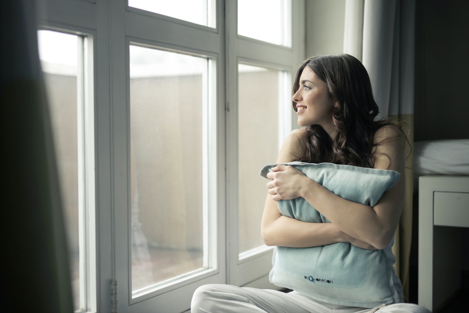 woman hugging pillow looking out new windows