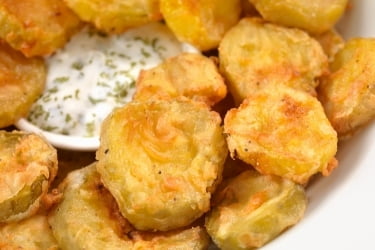 Close up photo of fried pickles with sauce