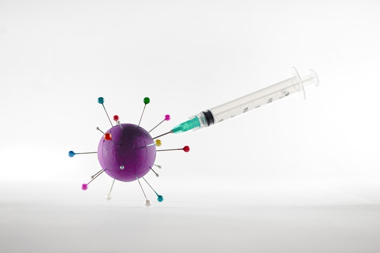 Syringe injecting a stylised coronavirus particle