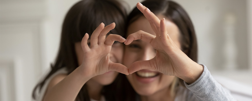 Mom and daughter making heart shape with joined hands