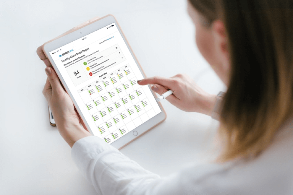 A woman checking Soberlink reporting on her tablet