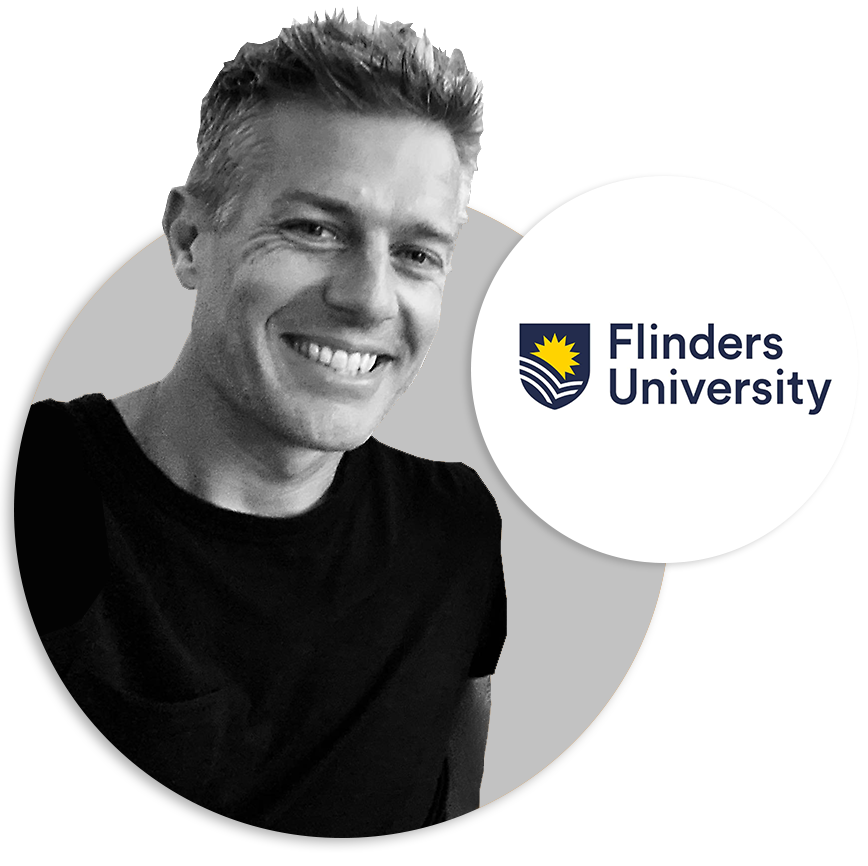 A man with a black t-shirt smiling next to the Flinders University logo.