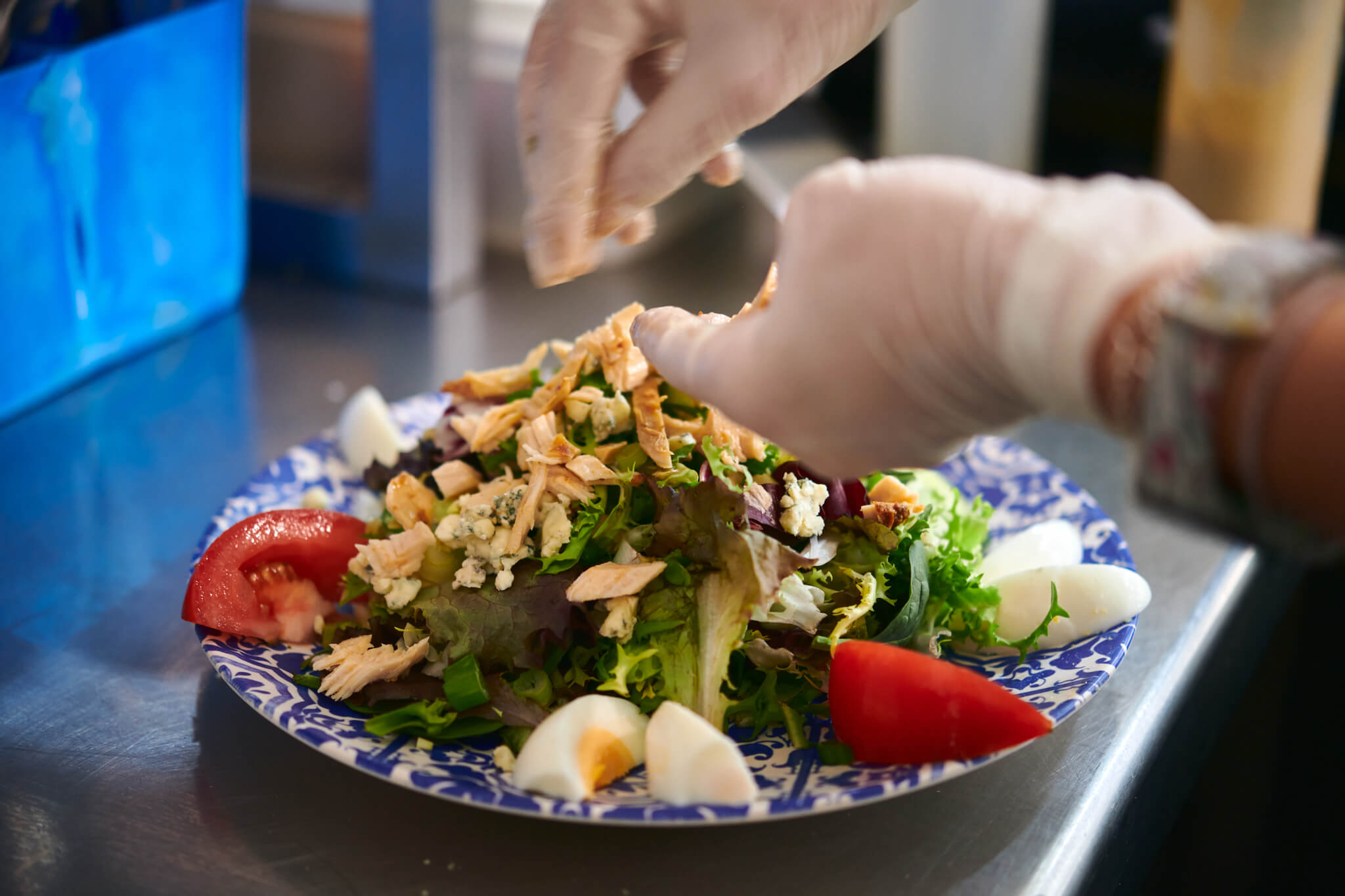 Someone sprinkling ingredients on a salad