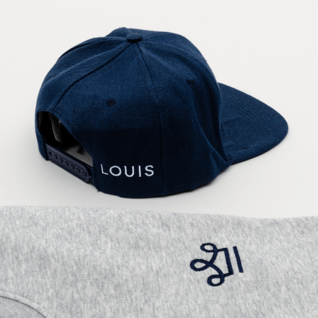 Pull gris et casquette bleu brodés avec le logo louis