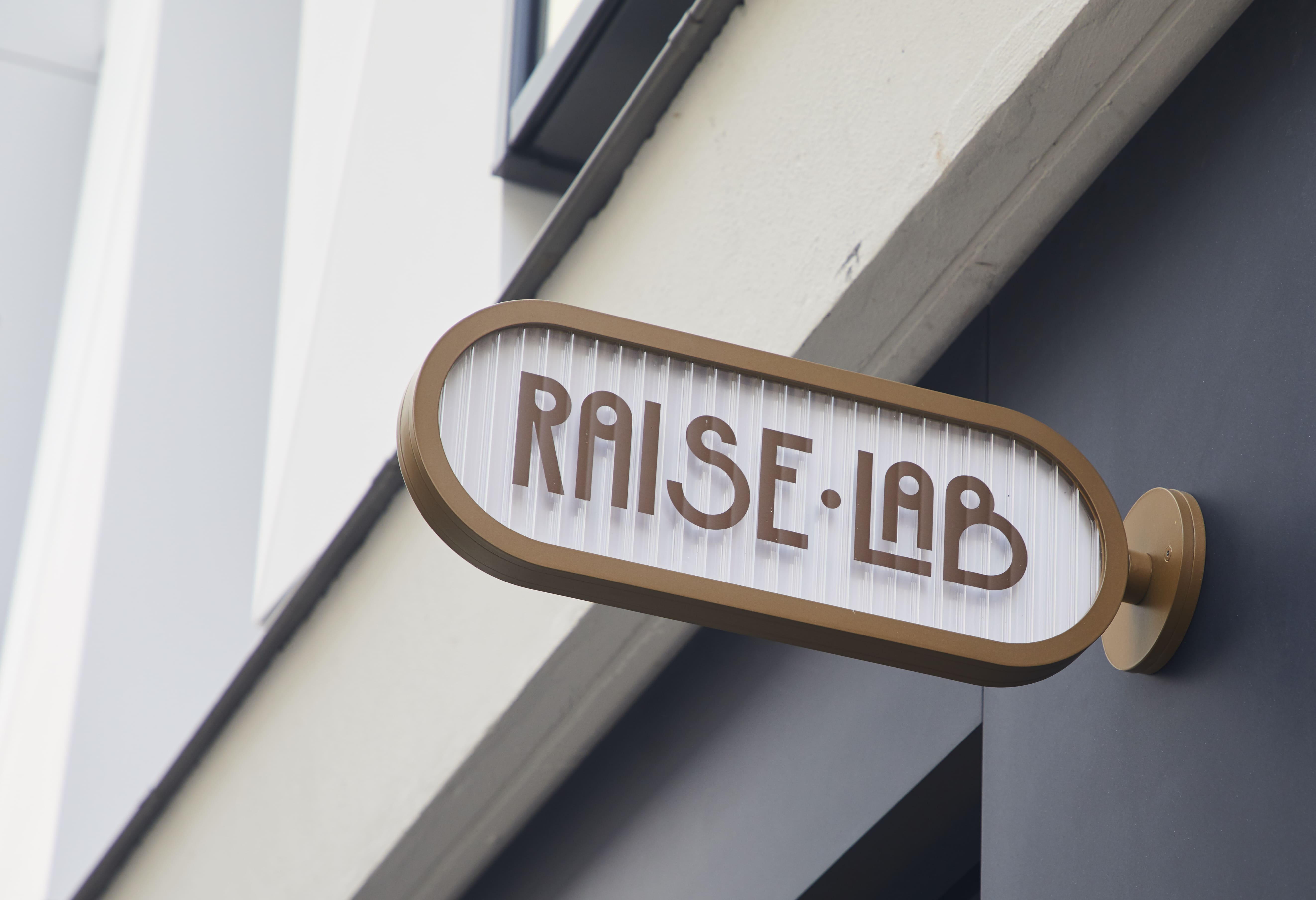 Logo du groupe RaiseLab accroché sur un mur d'un bâtiment