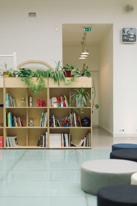 Meuble bibliothèque en bois avec un bac à plante sur le dessus, aménagé dans un espace de travail.
