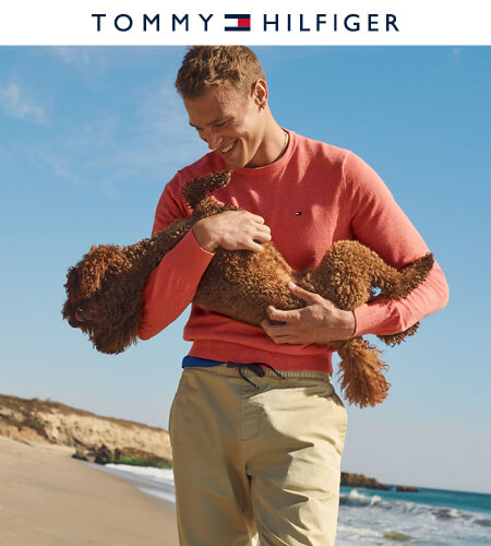 Young man wearing Tommy Hilfiger clothes on the beach holding his dog