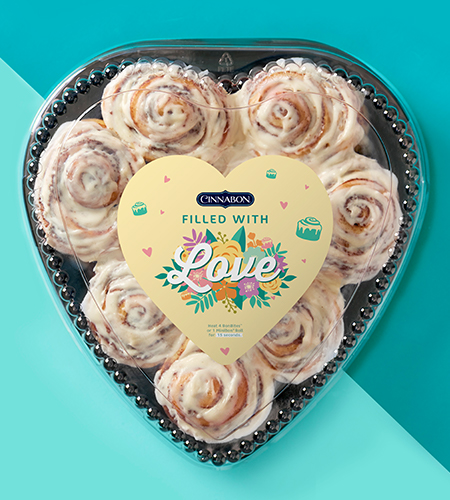 cinnabons in a heart shaped cinnabon box on a teal background